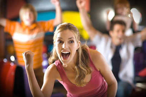 A joyful woman celebrating with her fist raised, surrounded by people showing excitement in the background.
