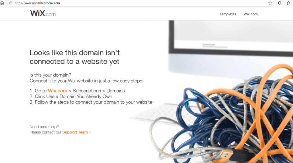 A cluttered mess of blue and silver cables on a desk with a computer keyboard and monitor in the background, indicating a disorganized digital workspace.